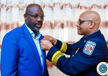 US Fire Marshall, John Butler pins President Weah with United States Fire Department flag pinEXECUTIVE MANSION